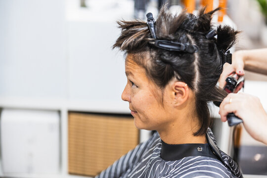 Woman client having hair styled in salon