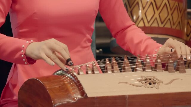 Woman in red playing on 16-stringed Dan Tranh (gayageum, kayagum) - traditional Vietnamese musical&nbsp;instrument