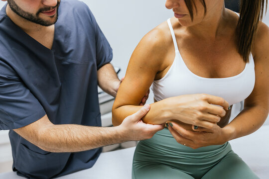 Physiotherapist examining woman's elbow joint for mobility test