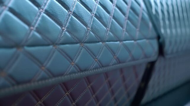 Samples of a stitched fabric for car seats are presented at the exhibition. Closeup. Shot in motion. Follow focus