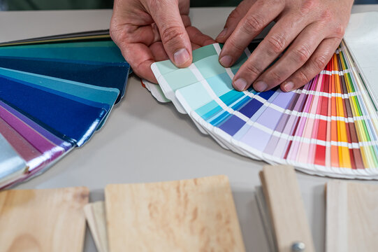 Architect Hands Pointing at Color Palette Swatch Fan and Wood Texture Samples for Design
