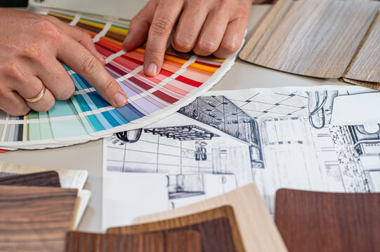 Architect Hands Choosing Color Palette Swatch Fan on Interior Sketch Blueprint Close up