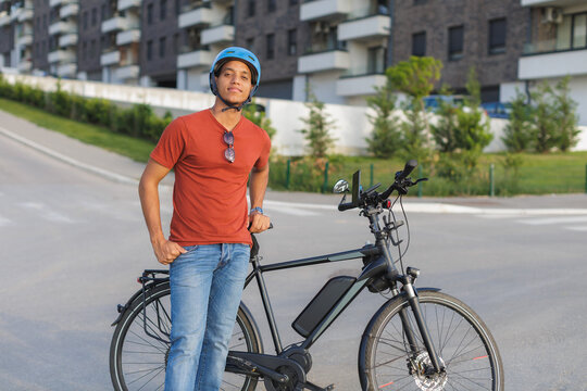 A man stands next to his electric bicycle on a street in a city