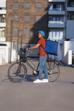 Delivery person with electric bike waits in the city street