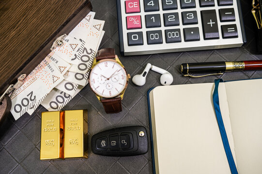 Close up of Luxury Men Watch Fine Gold Bar and Money Cash Stack on Modern Leather Business Desk