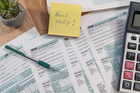 Top View of Tax Form 1040 with Need Help Note and Laptop on Desk for Financial Advisory Concept