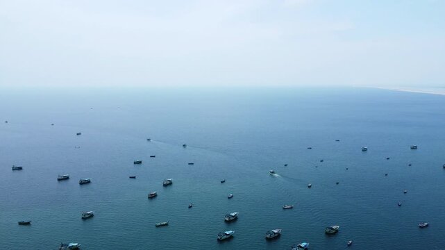 High Angle Aerial View of Multiple Indian Fishing Boats Anchored Near Harbor Coast in Open Sea. Indian Fishing Trawlers and Boats Floating on Calm Blue Ocean Water.