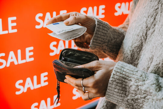 Person taking euro banknotes from wallet during sale shopping.