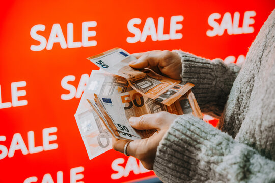 Person holding euro banknotes during sale shopping.