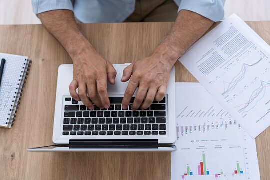 Top view of man's hands typing on computer keyboard closeup, businessman using laptop at office