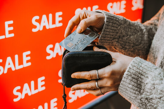Person taking bank card from wallet during sale shopping.