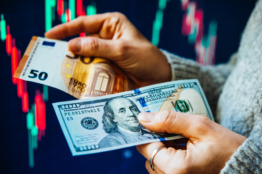US dollars and euros in front of the stock exchange screen showing trading graphics.