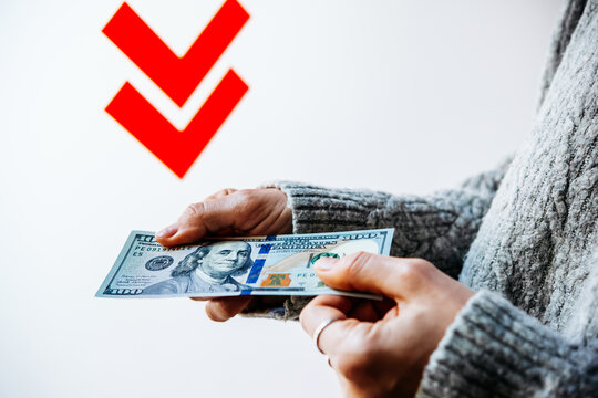Hands holding U.S. dollars with contrasting downward arrows.