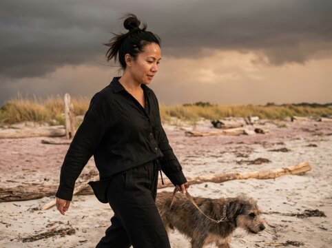 Moody beach walk with woman and dog at dusk