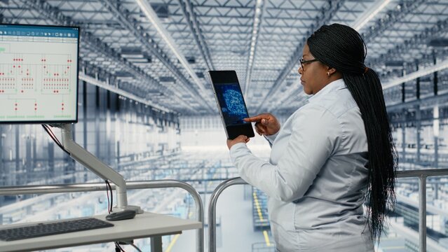 Woman and coworker optimize microchip smart factory workflow with EDA software, using simulation tools to track semiconductor production and circuit defects.