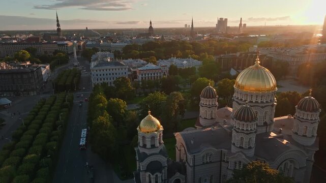 Cathedral golden domes and Freedom Monument Milda from drone at sunset, Riga. Aerial shot circling the orthodox Nativity of Christ Cathedral in Riga, Latvia.