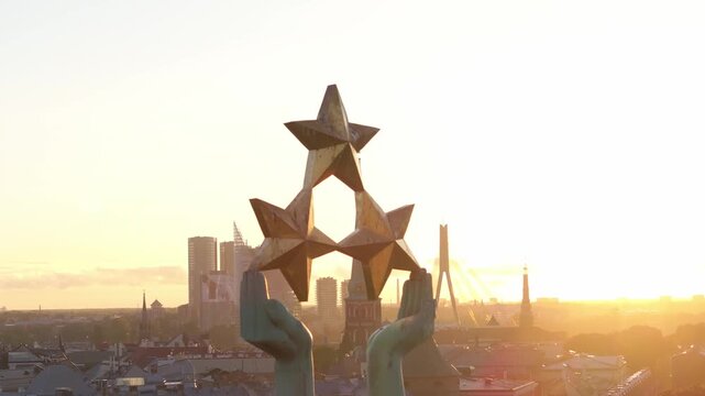 Three golden stars in Freedom Monument Milda hands from close drone, Riga. Close aerial orbit around the raised hands of the Liberty statue in Riga, Latvia, with Dome cathedral.
