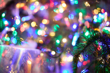 close-up of a Christmas tree branch with colorful glowing garland lights and bokeh, festive holiday concept,  New Year celebration, winter holidays, festive decorations, seasonal greetings © m.zh