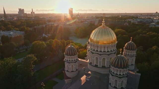 Cathedral golden domes in sun flare from orbiting drone, Riga. Aerial shot circling the cupolas of the orthodox Nativity of Christ Cathedral in Riga, Latvia.