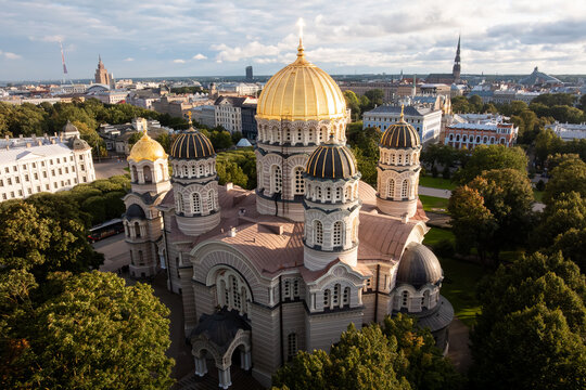 Nativity of Christ Cathedral golden domes at sunset from drone, Riga, Latvia. Drone close view of the orthodox church cupolas and crosses glowing in warm light with St Peters spire.