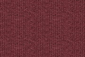 A full-frame, detailed close-up shot of wine red color knitted wool fabric texture. Characteristic vertical ribbed knit pattern and soft yarn fibers. Top down view © DariaR