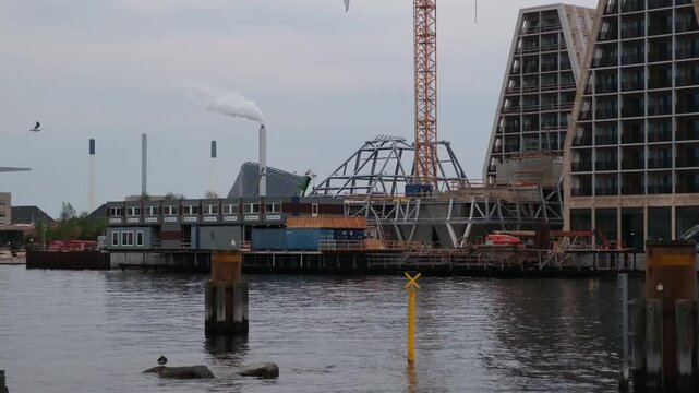 Construction site on Copenhagen waterfront in Denmark with modern architecture and cranes