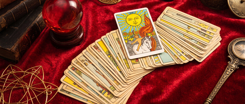 Fortune teller and whitcraft concept with tarot cards spread on red velvet surrounded by a magic crystal ball, gold bracelet, a book and a wooden box