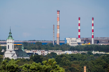 Widok na Ostrowiec Świętokrzyski. Na pierwszym planie widoczny jest kościół św. Michała Archanioła z białą fasadą i zielonym dachem. W tle wyróżnia się Huta Ostrowiec z kilkoma wysokimi kominami. © Grzegorz