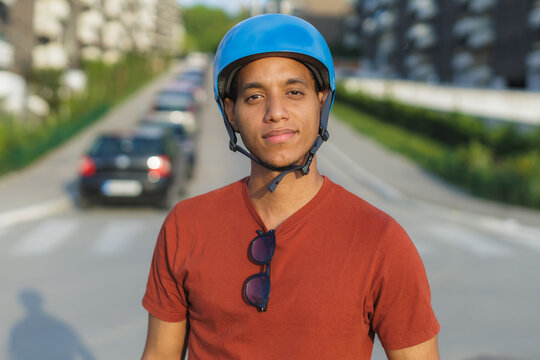 Young mixed race man wearing a blue helmet poses on a street