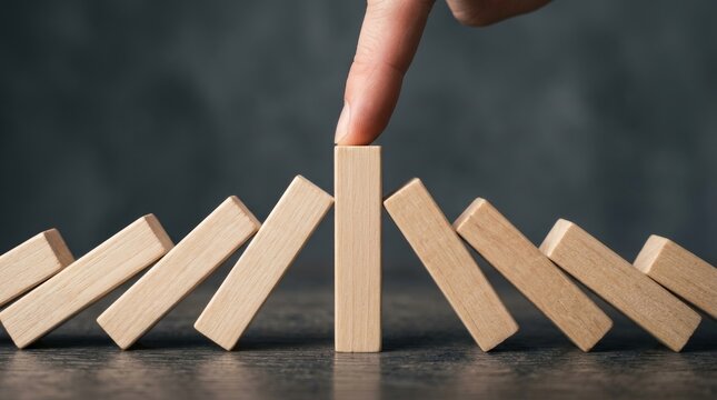 A hand stopping a domino effect to manage resource limits and protect focus.