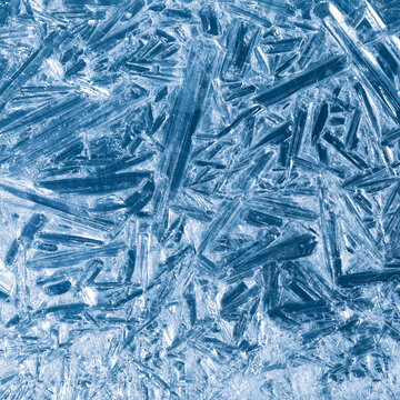 Ice frozen in intricate patterns of delicate crystals with brilliant contrasts of deep blues. Real unique patterned crystal formations. Sparkling window frost or icy cold winter frosting background.