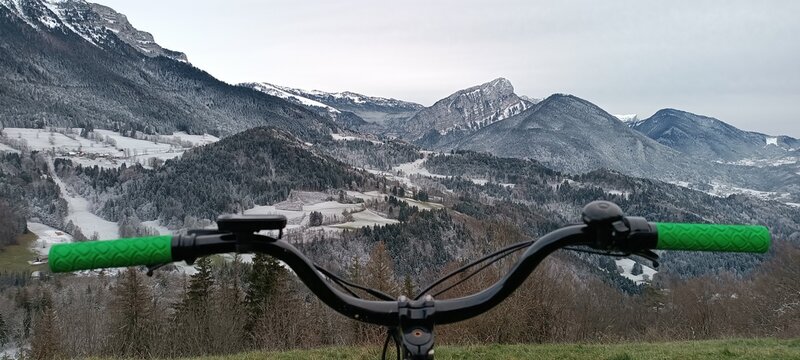 un magnifique paysage de montagne l&eacute;g&egrave;rement enneig&eacute;, observ&eacute; depuis le guidon d'un v&eacute;lo tout-terrain, au-dessus d'une vaste vall&eacute;e alpine