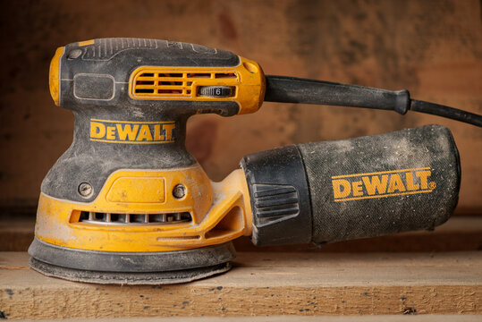 DeWalt brand Orbital Sander with dust on a wooden surface in a workshop setting