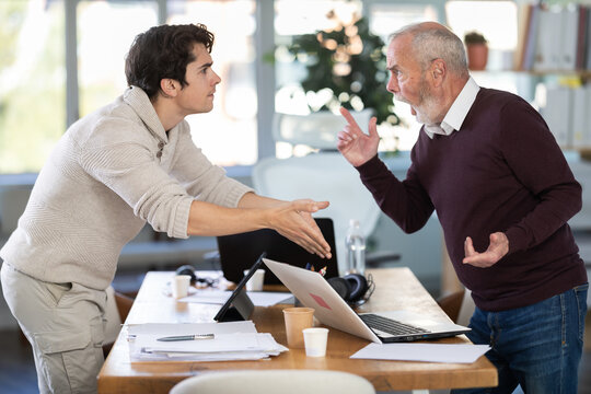 Quarrel between two managers in office - an elderly man and young man shout at each other, dissatisfied with their work