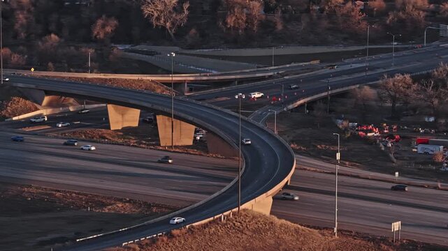 Highway interchange with heavy car traffic moving on overpasses and ramps during a warm sunset denver