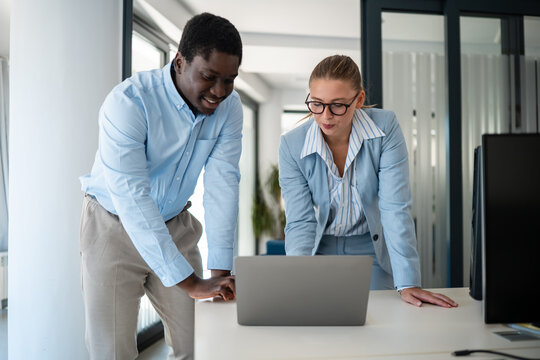 Business colleagues collaborating on laptop in modern office setting