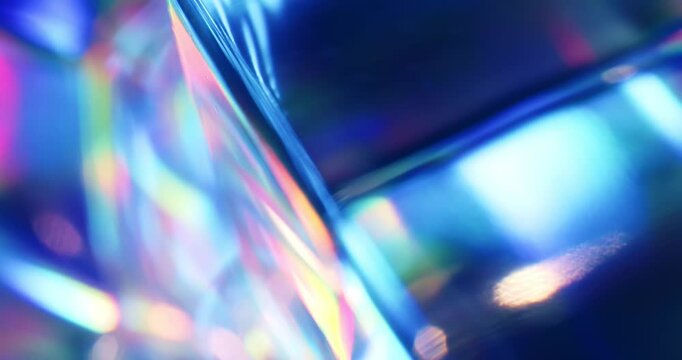 Light reflecting glass in brilliant saturated colors. Radiant lighting through a prism creating a visual of a rainbow effect of colorful light refraction. Spinning geometric cube abstract background.