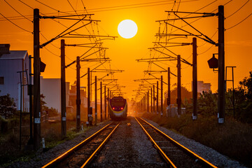 Passenger train approaches along railway tracks at golden sunset © 柏佑 鄧