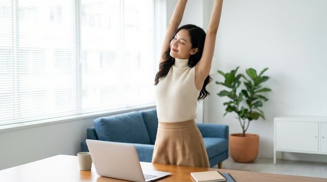 Relieving stress, a young Asian businesswoman stretches her arms at her workplace.