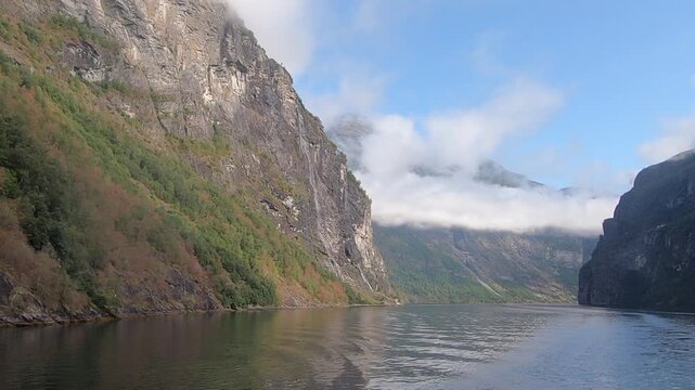 Boat sails through parts of Geiranger Fjord, steep mountain walls, M&oslash;re og Romsdal, Norway