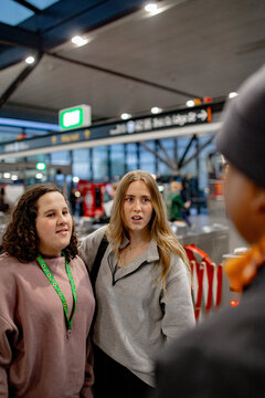 Teen girl and support worker standing together and talking with another commuter