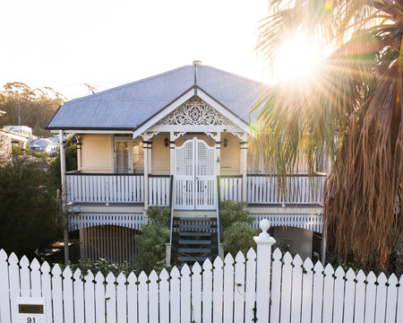 Elevated timber house enclosed with white picket fence with pointed tops