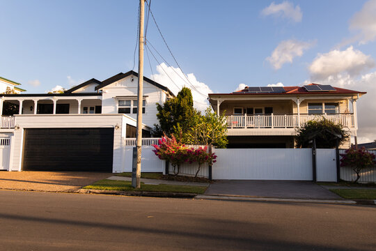 Streetview of a two-story suburban home with a red roof and beige weatherboard exterior