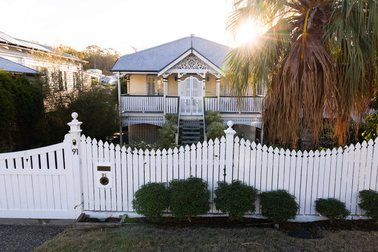 Elevated timber house enclosed with white picket fence with pointed tops