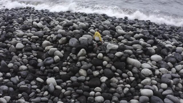 Drone shot, from above, man on the coast with large round stones in Rocha da Relva, Sao Miguel Island, Azores, Portugal