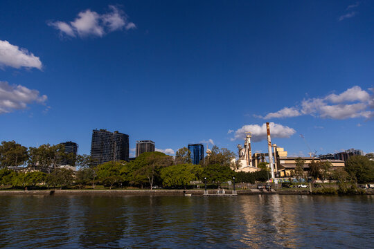 a factory on the bank of a river with city buildings behind
