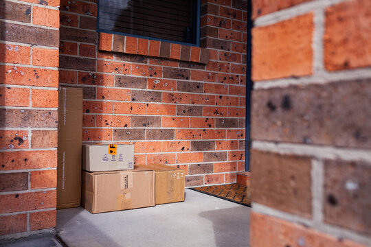 Cardboard boxes piled outside door of house from online home delivery orders