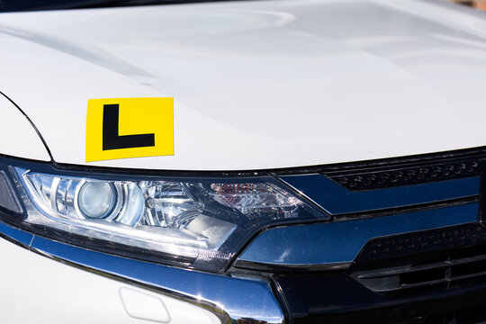 Magnetic yellow L plate for learner driver on car parked on driveway