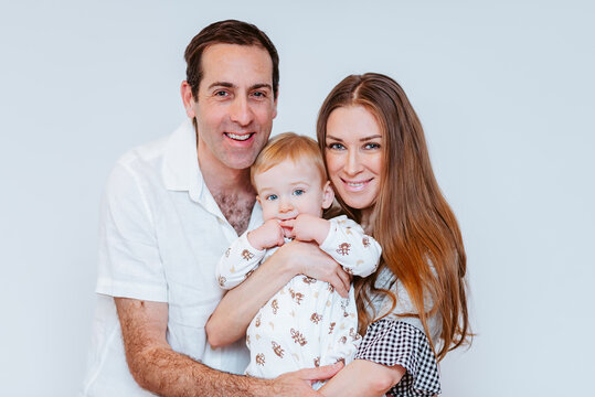 Parenthood happiness: a man and woman with their child in a studio setting, white background