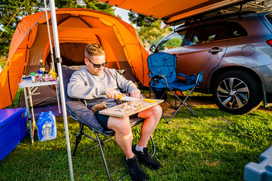 Person chopping food under orange camping canopy outdoors